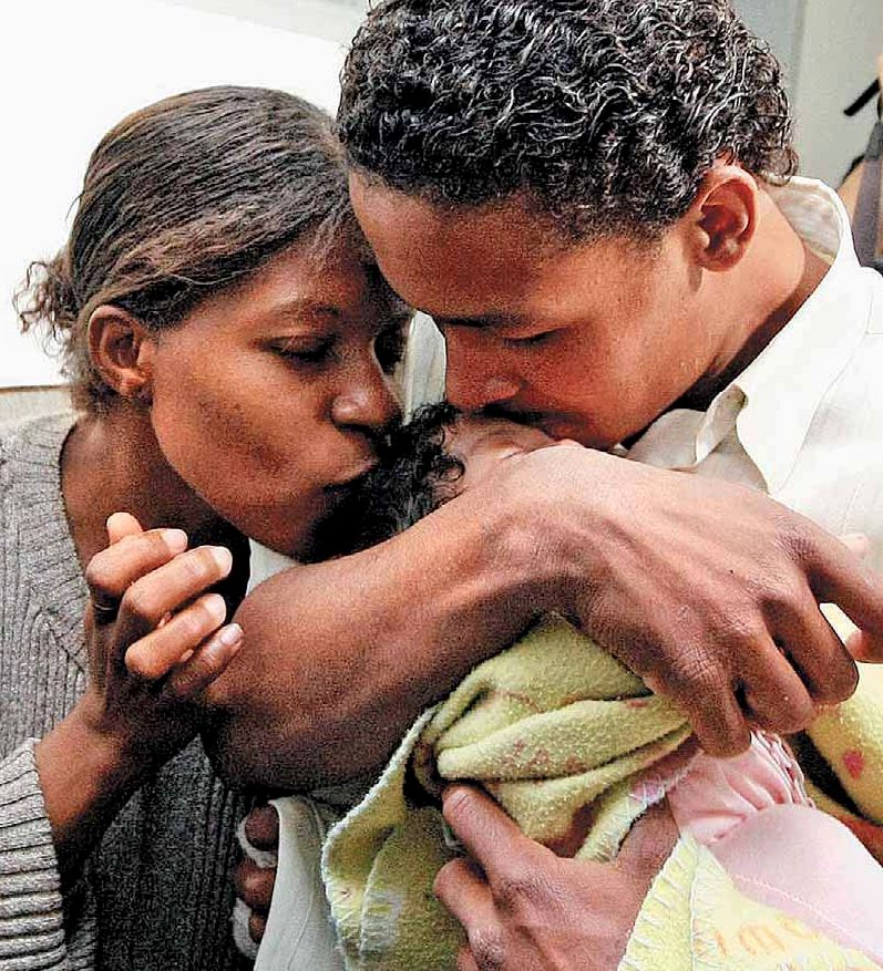 Mamma e pap abbracciano e baciano la loro figlia, di un mese di vita, dopo un tentativo di rapimento della piccola