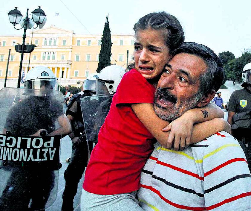 Padre e figlia respinti dalla polizia, protestano davanti al Parlamento ad Atene (Grecia) contro le misure economiche; fonte Tsironis