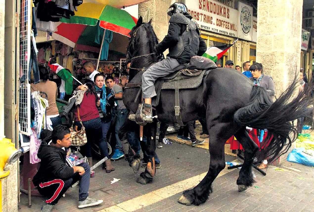 poliziotto israeliano disperde palestinesi in protesta a Gerusalemme, alla "Porta di Damasco", nell'anniversario della creazione dello Stato di Israele; fonte Guez